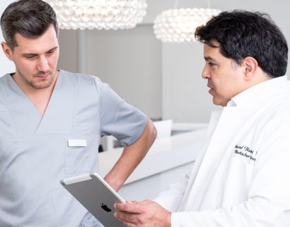 Arzte bespricht mit einem Mitarbeiter weitere Patientenbehandlungen
