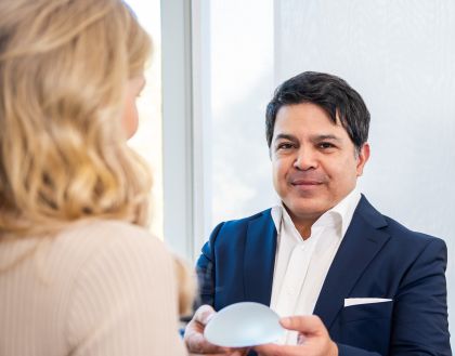 Massud Hosseini, Facharzt für Plastische & Ästhetische Chirurgie, zeigt einer hübschen Patientin ein Implantat