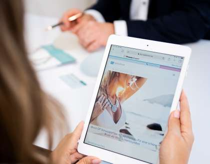 Dunkelblonde Frau schaut sich auf einem Tablet eine Webseite mit Behandlungsmöglichkeiten an
