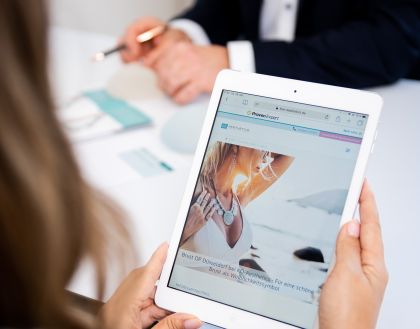 Dunkelblonde Frau schaut sich auf einem Tablet eine Webseite mit Behandlungsmöglichkeiten an
